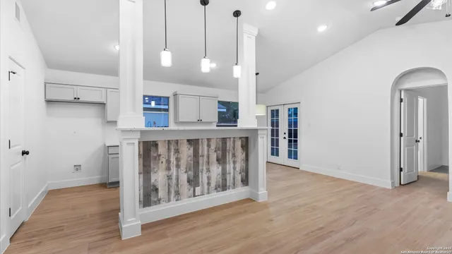 a view of an empty room with wooden floor and windows
