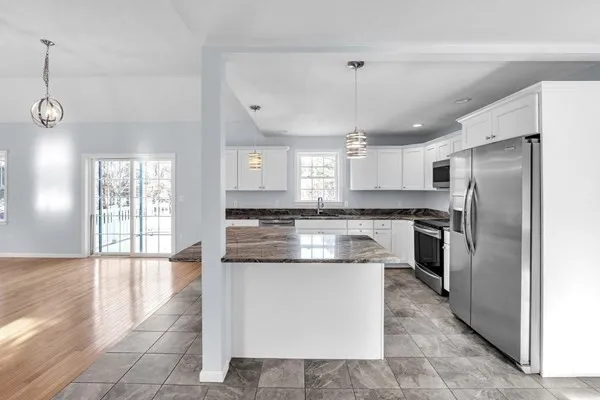 a large kitchen with kitchen island a large counter top and stainless steel appliances