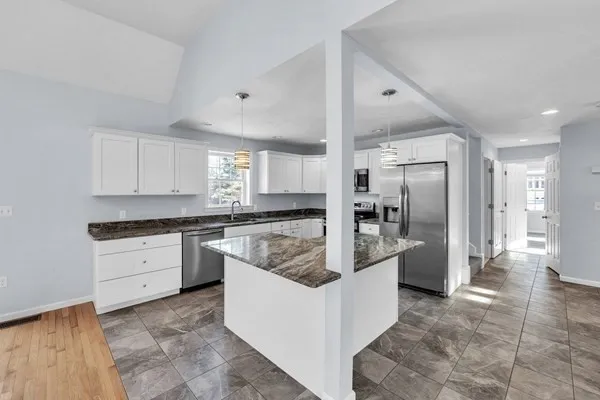 a large kitchen with stainless steel appliances kitchen island granite countertop a refrigerator and a sink