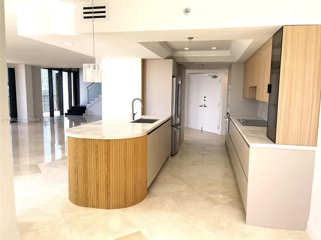 a view of an empty room with kitchen and a window