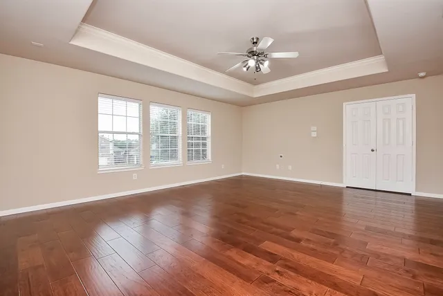 a view of an empty room with wooden floor and a window
