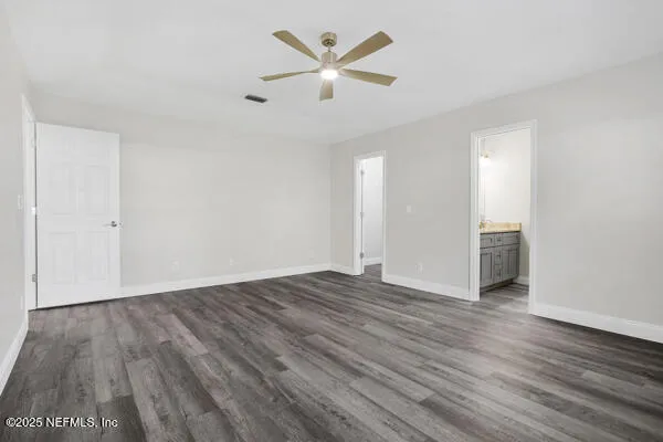 an empty room with wooden floor and a ceiling fan