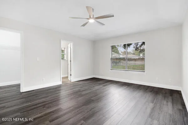 an empty room with wooden floor chandelier fan and windows