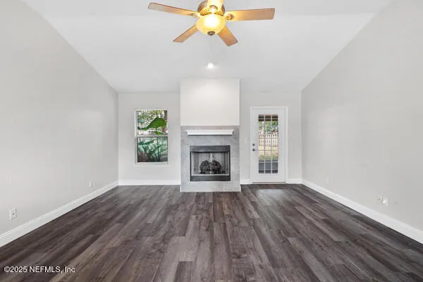 a view of an empty room with wooden floor fireplace and a window