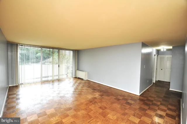 an empty room with chandelier fan and windows