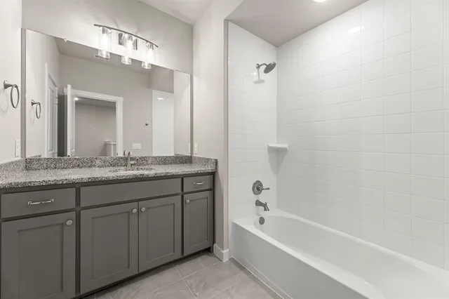 a bathroom with a granite countertop bathtub a sink and a mirror