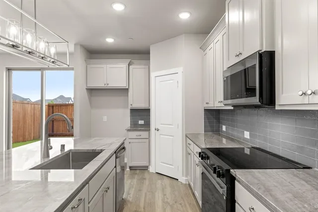 a kitchen with kitchen island granite countertop a sink a stove and cabinets