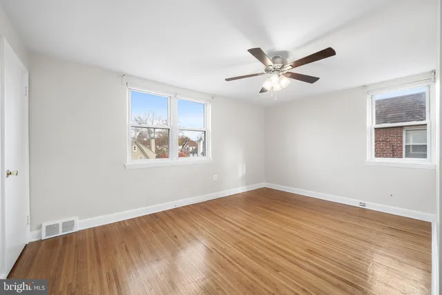a view of an empty room with window and wooden floor