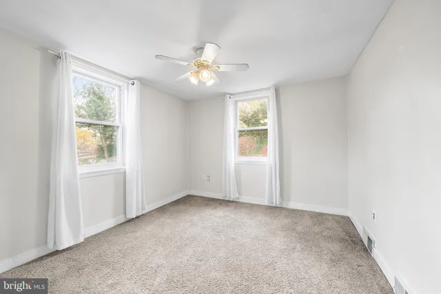 an empty room with windows and fan