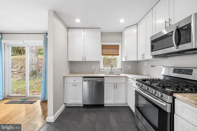 a kitchen with stainless steel appliances white cabinets a sink and a stove