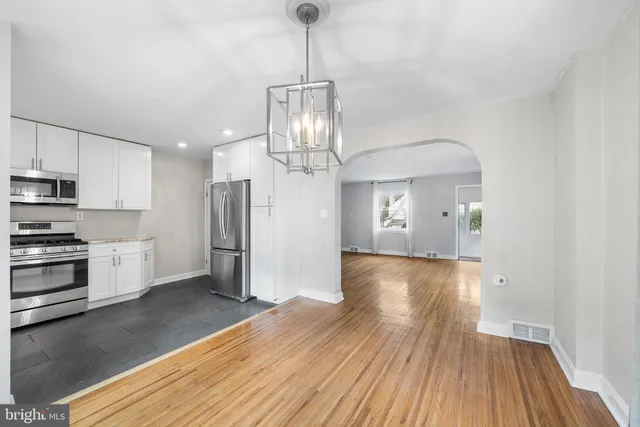 a view of a kitchen with wooden floor electronic appliances and a ceiling fan