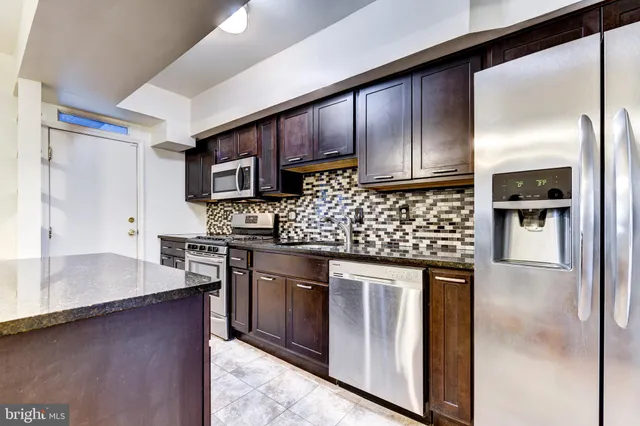 a kitchen with stainless steel appliances granite countertop wooden cabinets a stove top oven a sink and dishwasher