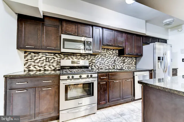 a kitchen with stainless steel appliances granite countertop wooden cabinets stove top oven and refrigerator