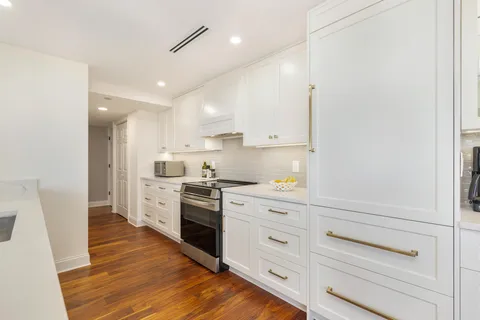 a kitchen with granite countertop white cabinets and white appliances