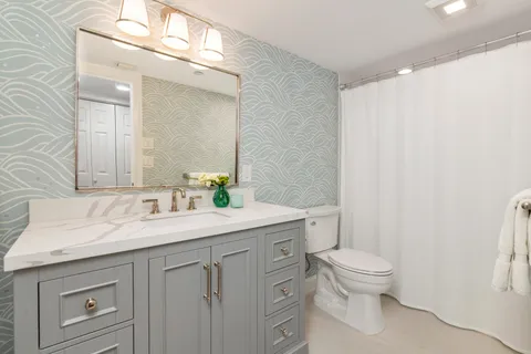 a bathroom with a granite countertop sink a toilet and a mirror