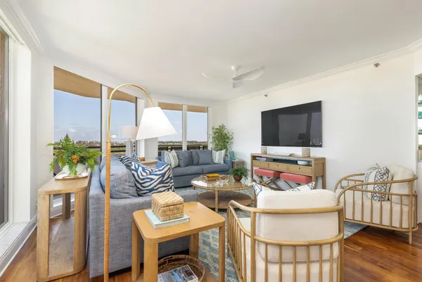 a living room with furniture a flat screen tv and a floor to ceiling window