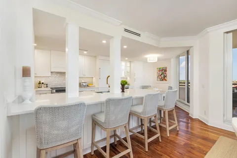 a kitchen with stainless steel appliances kitchen island granite countertop a dining table chairs and sink