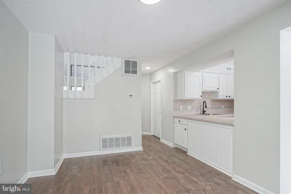 a room with white cabinets and wooden floor