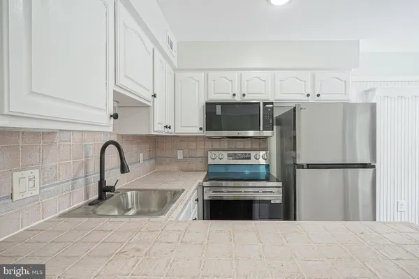 a kitchen with stainless steel appliances a refrigerator sink and white cabinets