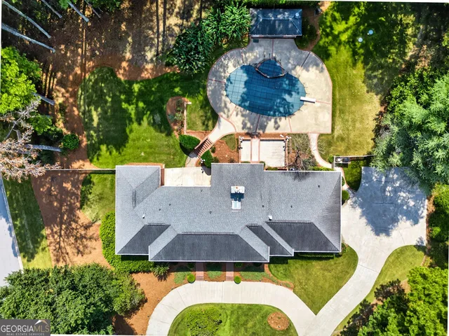 an aerial view of a house with swimming pool and large trees
