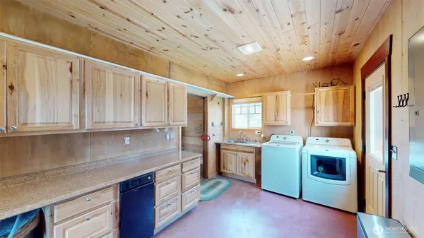a kitchen with stainless steel appliances granite countertop a sink a stove a refrigerator a washer dryer and white cabinets