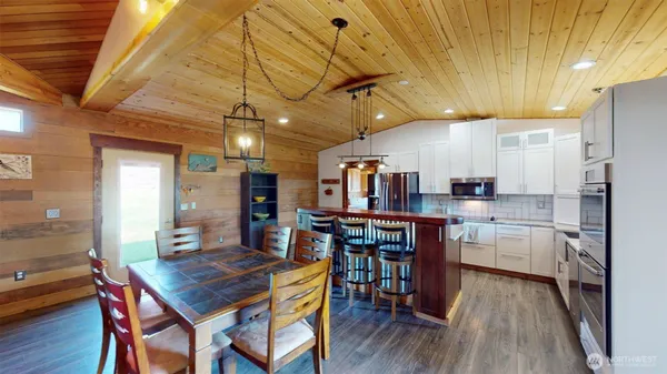 a kitchen with stainless steel appliances granite countertop a table chairs refrigerator and microwave