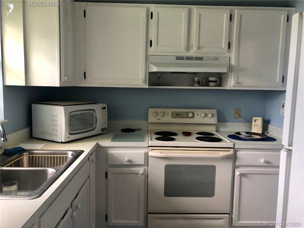 1225 Northwest 21st Street, Unit 2908 Stuart, FL 34994 - Photo 6 of 56 a kitchen with granite countertop white cabinets and white appliances