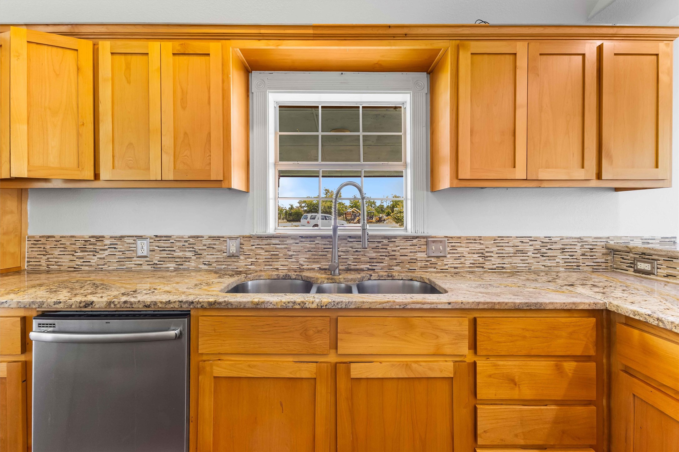 12212 Ballerstedt Road Elgin, TX 78621 - Photo 13 of 39 Kitchen with dishwasher, light stone countertops, and wood finish cabinets