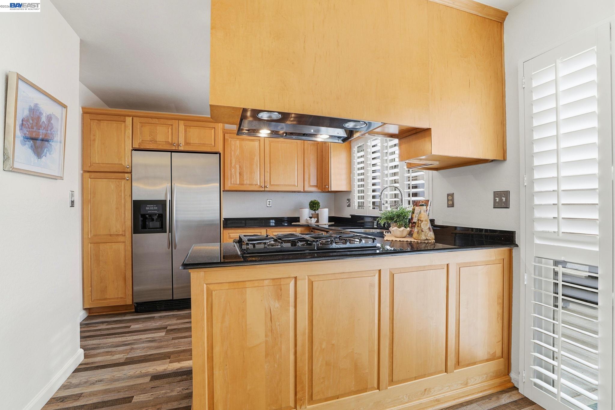 38524 Burdette Common Fremont, CA 94536 - Photo 15 of 35 a kitchen with granite countertop a refrigerator a sink and wooden cabinets
