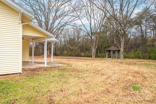 a view of a small house with large trees and a small yard