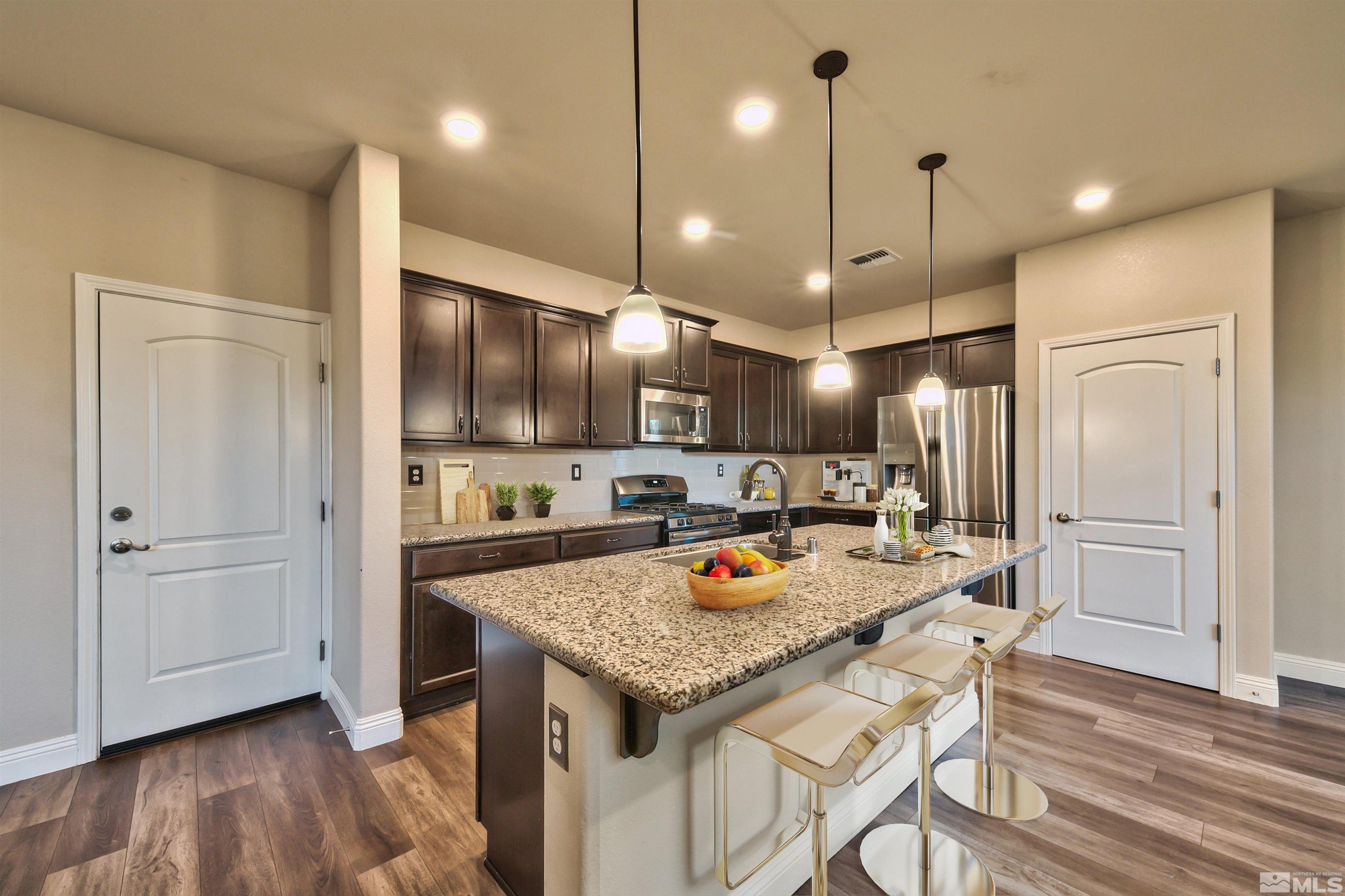 2330 Soprano Drive Reno, NV 89521 - Photo 8 of 29 a kitchen with stainless steel appliances granite countertop a kitchen island a stove a table and chairs
