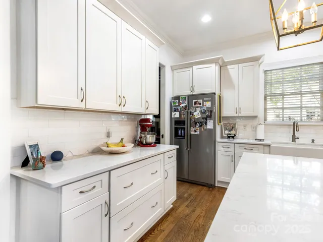 a kitchen with stainless steel appliances granite countertop a refrigerator sink and white cabinets