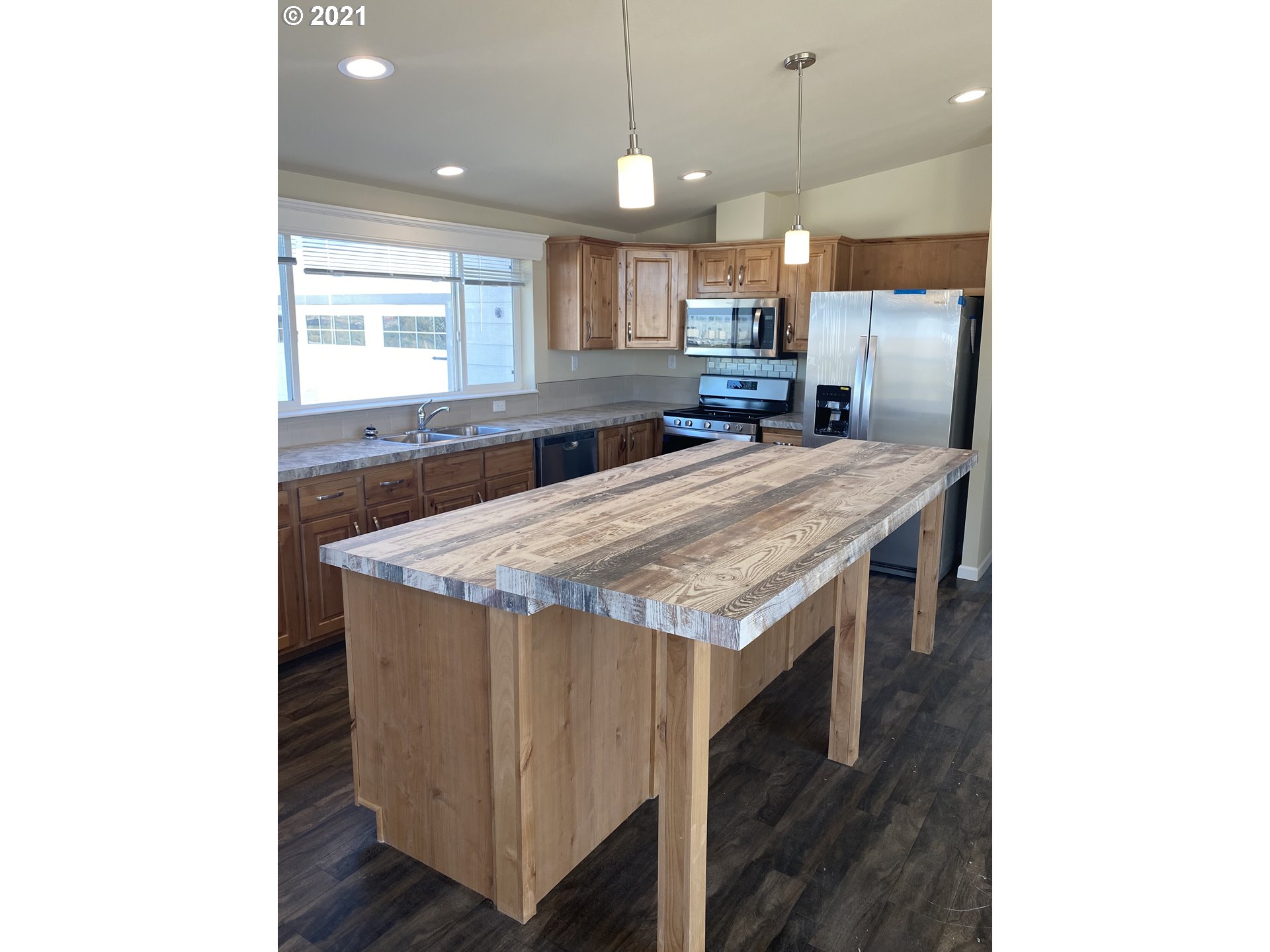 305 Oregon Trail Boulevard Boardman, OR 97818 - Photo 2 of 11 a room with kitchen island a sink dishwasher a dining table and chairs with wooden floor