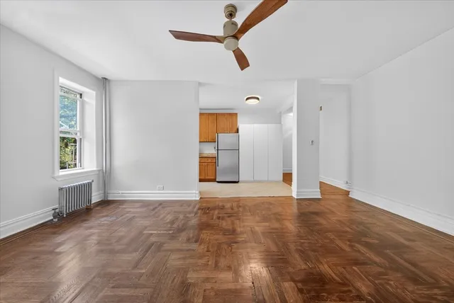 a view of an empty room with window and a kitchen