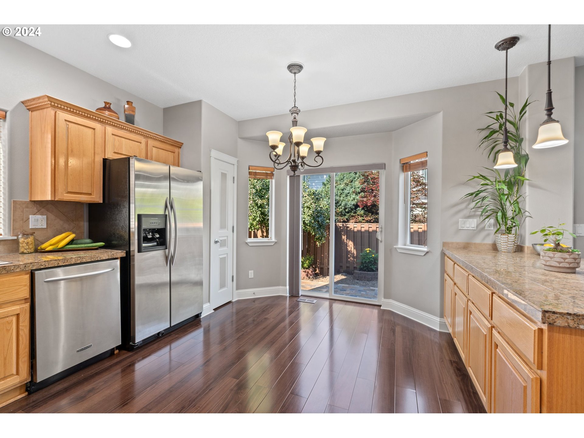 3779 Northwest 4th Way Hillsboro, OR 97124 - Photo 6 of 24 a kitchen with stainless steel appliances granite countertop a refrigerator a stove a sink dishwasher and a dining table with wooden floor