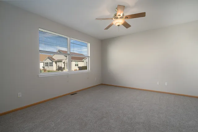 an empty room with windows and chandelier fan