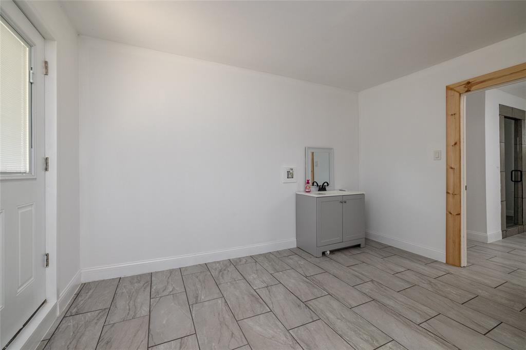 151 County Road 3699 Springtown, TX 76082 - Photo 15 of 35 Wood-look tile flooring in a rectangular pattern, white painted walls, and a white paneled door with an upper window