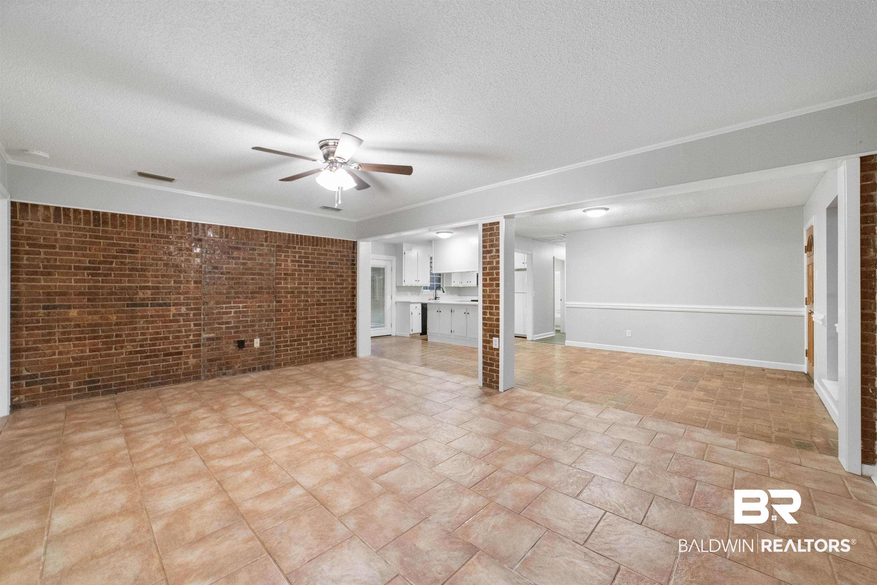 11833 Old Moffat Road Wilmer, AL 36587 - Photo 2 of 23 Unfurnished living room with a textured ceiling, brick wall, ceiling fan, and visible vents
