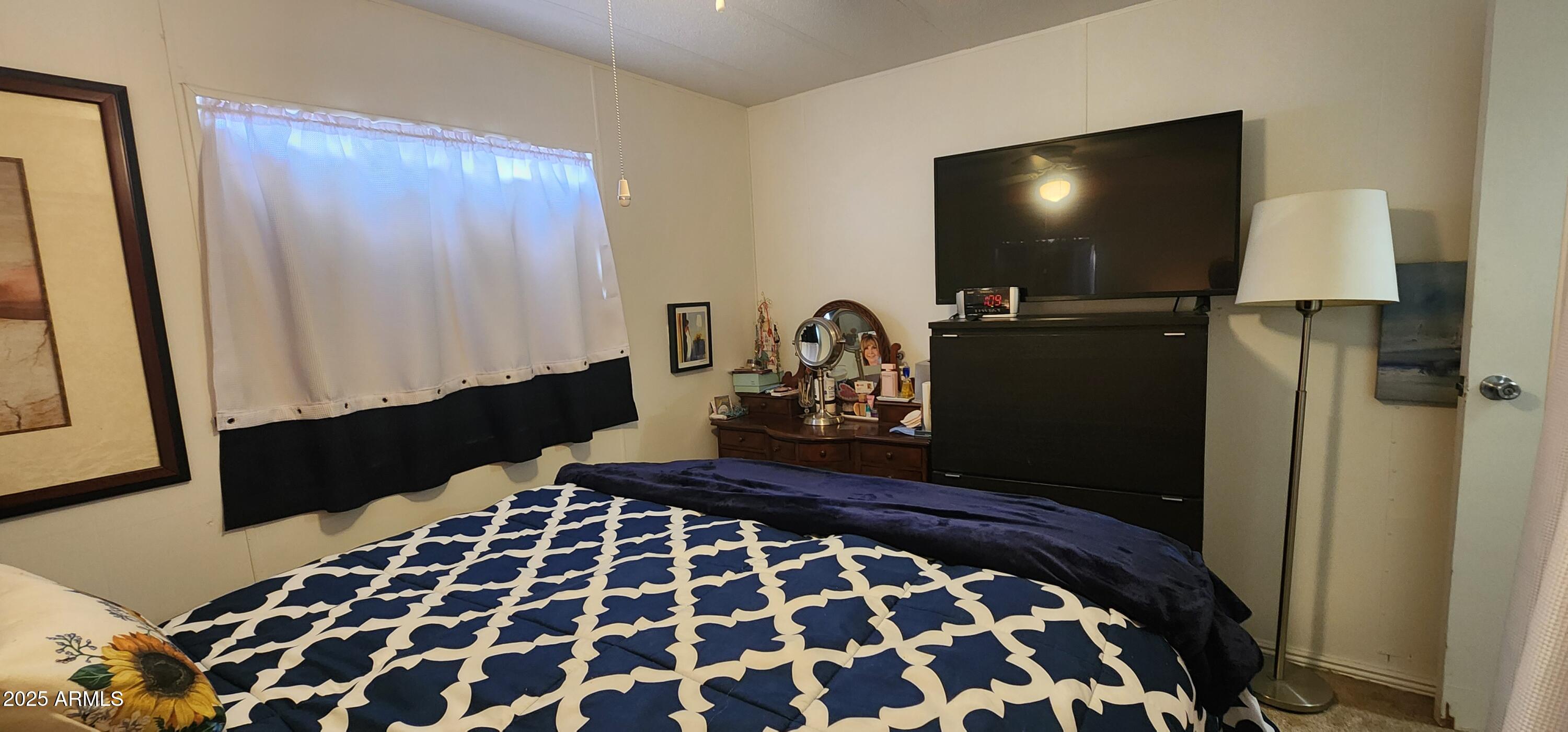 16005 North 32nd Street, Unit 33 Phoenix, AZ 85032 - Photo 16 of 40 a bedroom with a bed and a flat tv screen next to a window