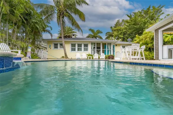 a view of a swimming pool with a garden and palm trees