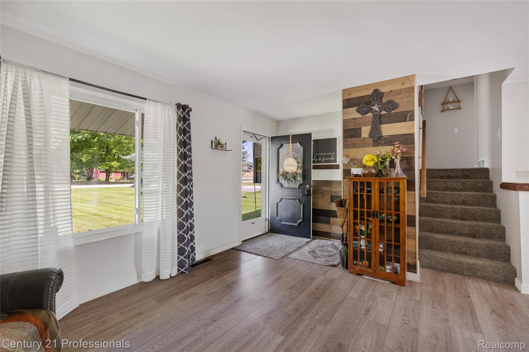 15037 Hogan Road Linden, MI 48451 - Photo 6 of 38 Entryway with wood-finish flooring, a black paneled front door, and a striking accent wall featuring horizontal wood planks
