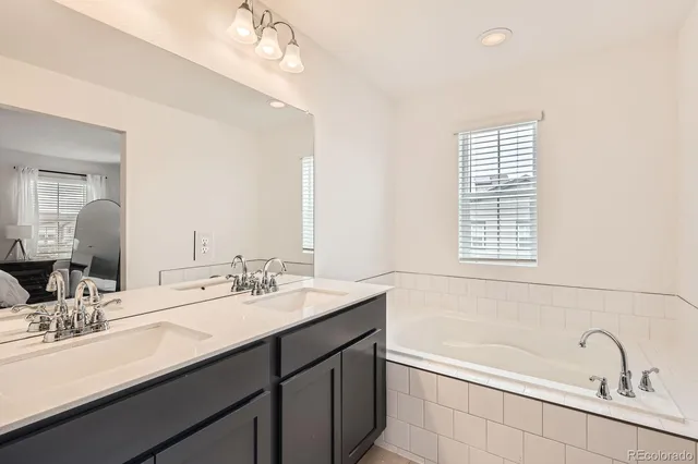 a bathroom with a double vanity sink mirror and bathtub