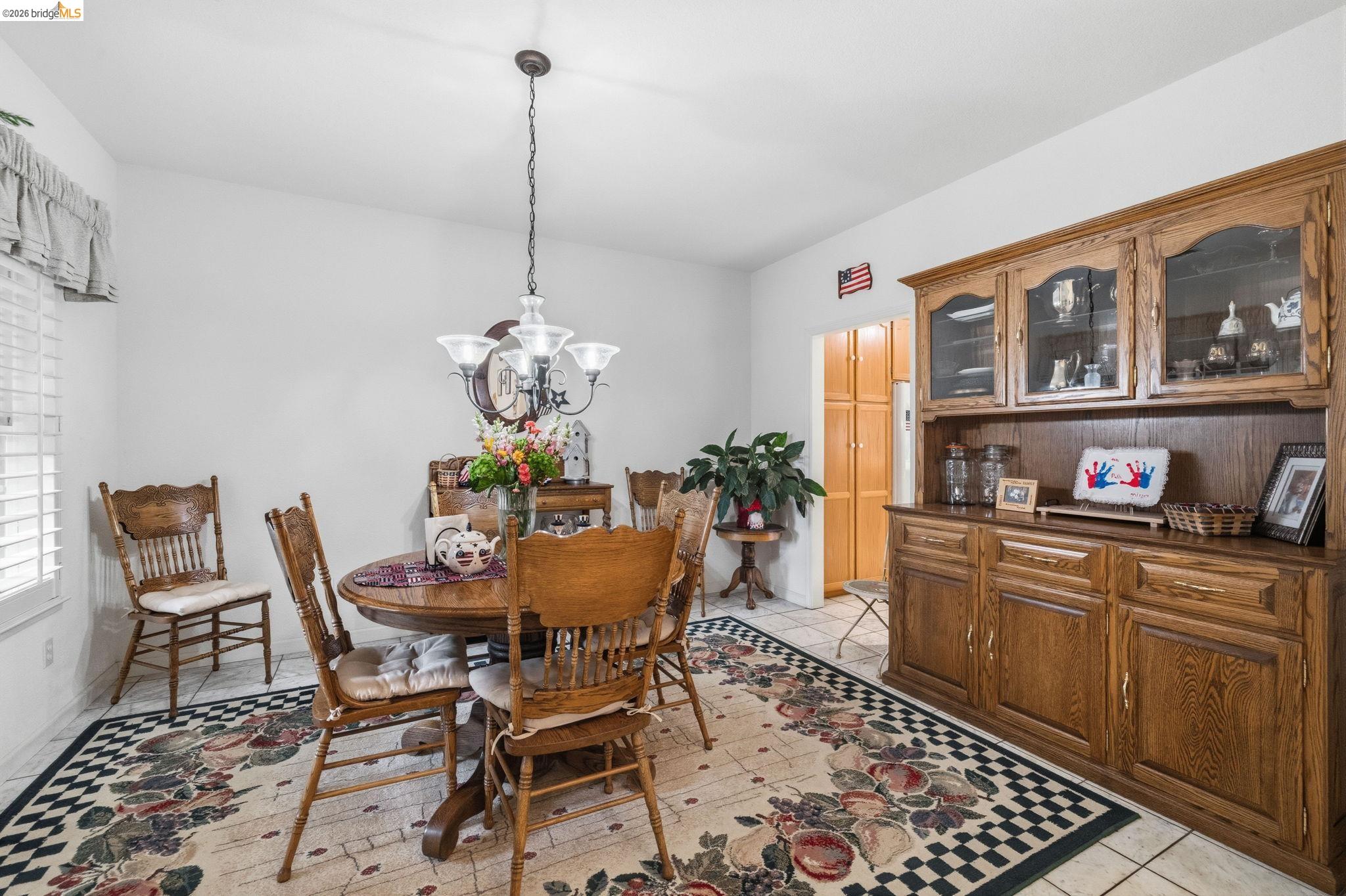18450 Lambert Lake Road Sonora, CA 95370 - Photo 18 of 87 Dining area featuring tile flooring, a prominent built-in wood hutch with glass-fronted upper cabinetry, a wood-finish interior door, and a multi-light chandelier