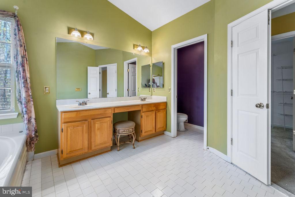14701 Danton Court Bowie, MD 20721 - Photo 31 of 60 a bathroom with a double vanity sink a mirror and a bathtub