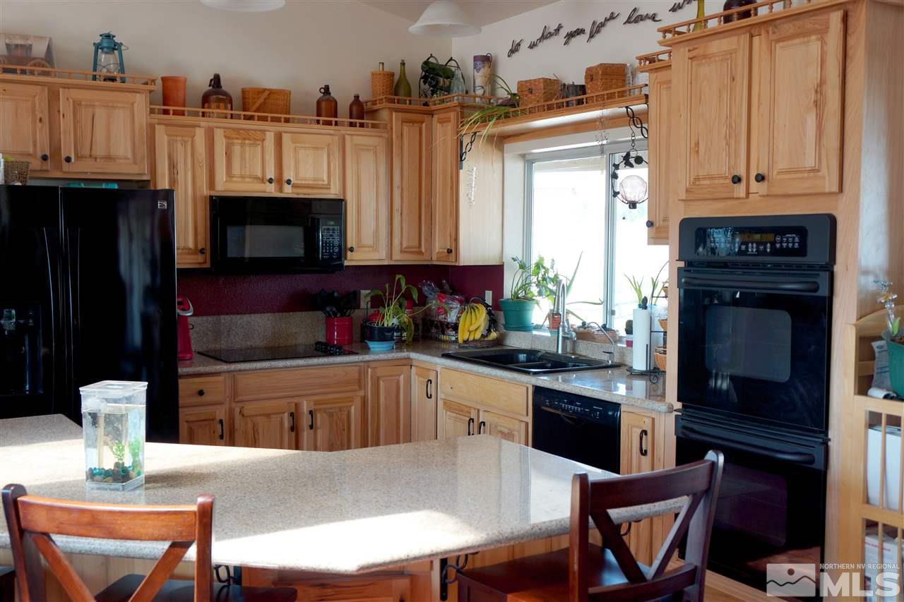 5200 Twin Springs Road Reno, NV 89510 - Photo 8 of 23 a kitchen with stainless steel appliances kitchen island granite countertop a table chairs microwave and sink