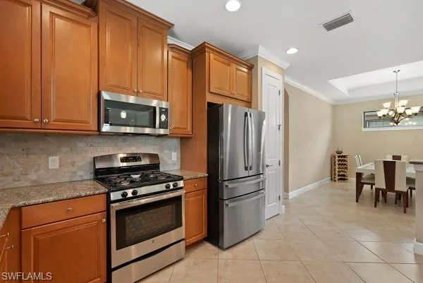 a kitchen with granite countertop a refrigerator and a stove top oven