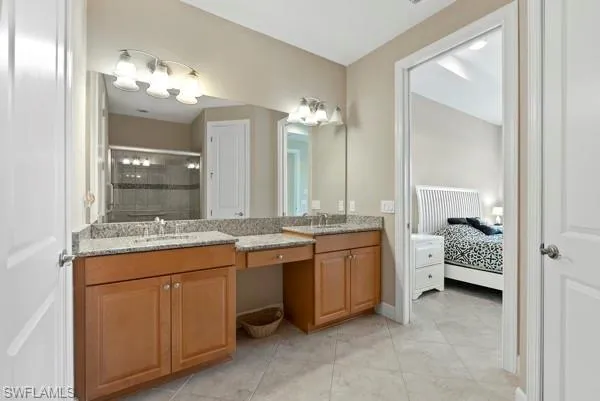 a bathroom with a granite countertop double vanity sink and a mirror