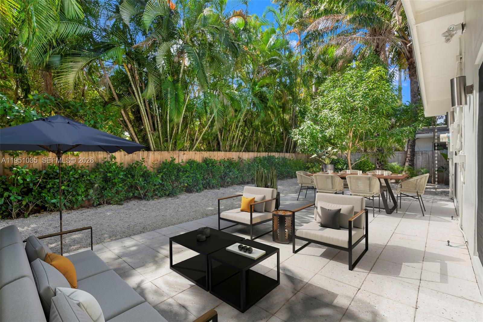 1040 Northeast 85th Street Miami, FL 33138 - Photo 20 of 22 a backyard of a house with table and chairs under an umbrella