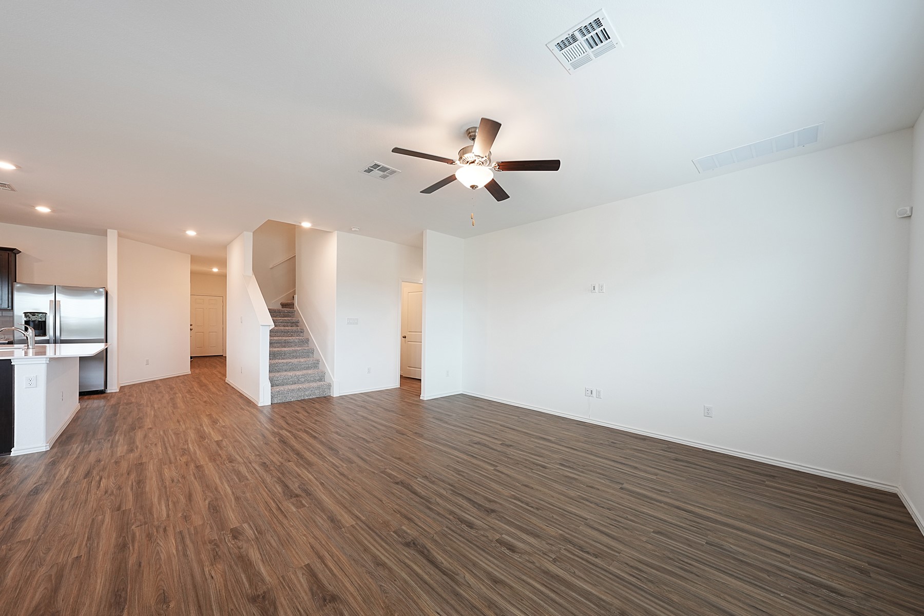 932 Mallow Road Leander, TX 78641 - Photo 34 of 34 An open floorplan with durable flooring connects the kitchen, living area, and a carpeted staircase.