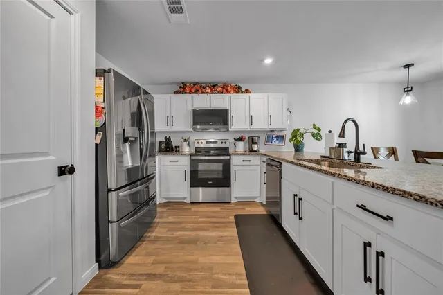 a kitchen with stainless steel appliances granite countertop a refrigerator and a sink